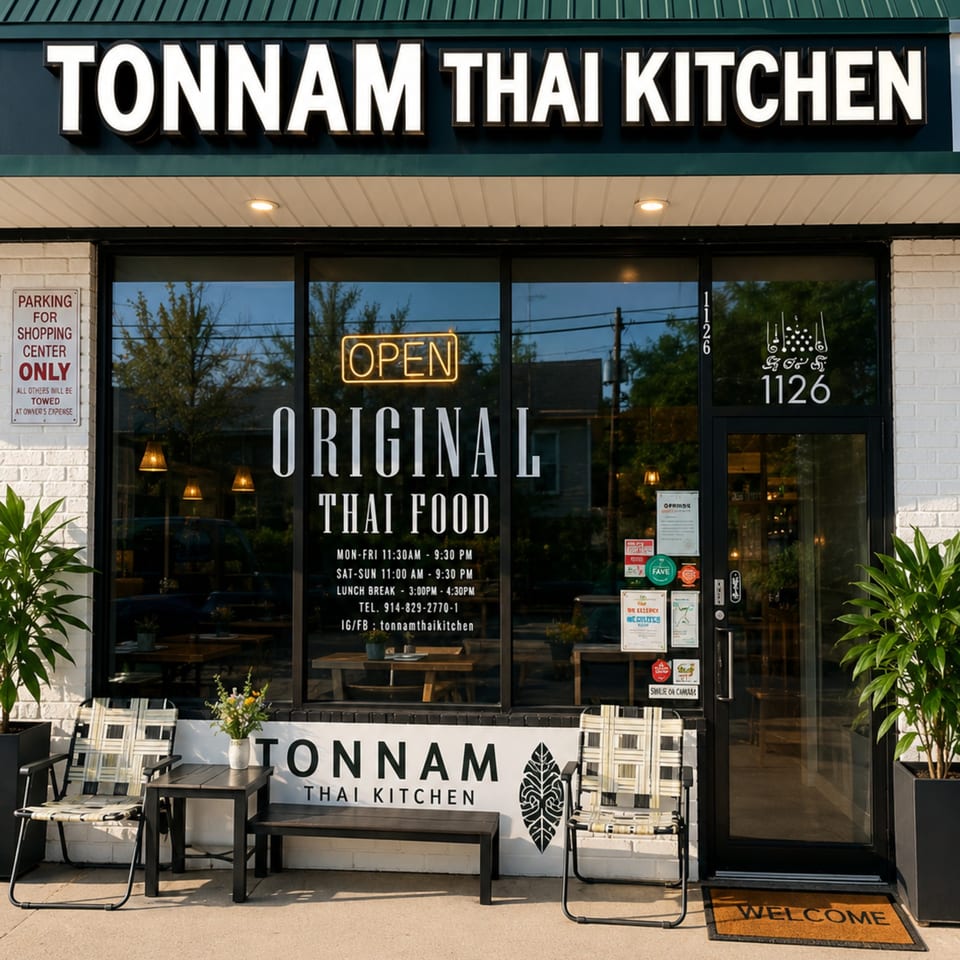 Exterior of Tonnam Thai Kitchen with an "OPEN" sign, outdoor seating, and menu details on the window.